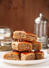 Oriental sweets with walnut in a white plate on a wooden table, vertical