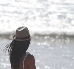 Beautiful girl, seen from behind, with hat who look the sea. Sea in the background. Sabaudia,...