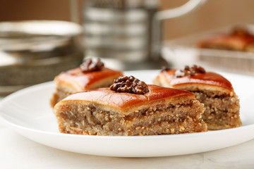 Oriental sweets with walnut in a white plate on a wooden table