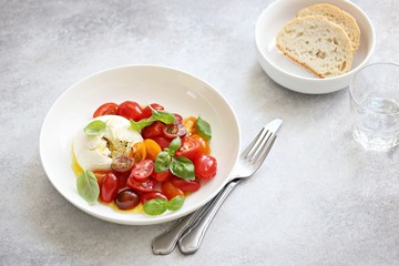 Mozzarella and cherry tomatoes salad with fresh basil and olives. 