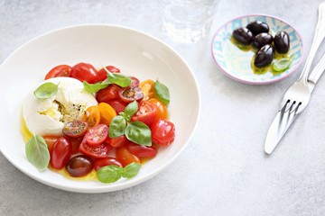 Mozzarella and cherry tomatoes salad with fresh basil and olives. 