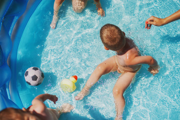 Baby kids playing at baby pool at backyard. Kids pool having fun. Summer day at home. Family time.