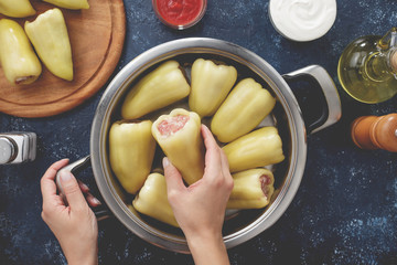 Hand puts raw stuffed pepper into the pan for cooking.