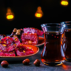 Turkish tea served in traditional style,oriental sweets,Rahat Lokum,dark background.Square picture.