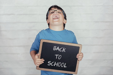 back to school, happy child with a blackboard on brick background