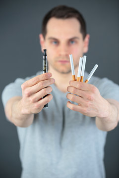 Man holding cigarettes in one hand and an electronic cigarette in the other hand