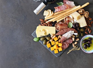 Mediterranean appetizers. Platter with tapas selection: jamon, cheese variety, olives and nuts.   Overhead view, copy space.