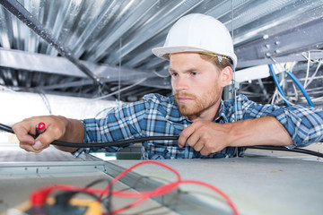 Electrician reaching into roof space