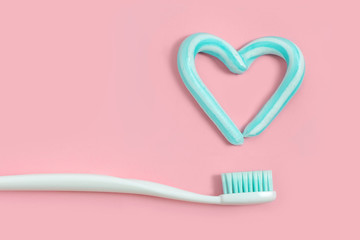 Toothbrushes and turquoise color toothpaste in shape of heart on pink background. Dental and healthcare concept. - 213624221