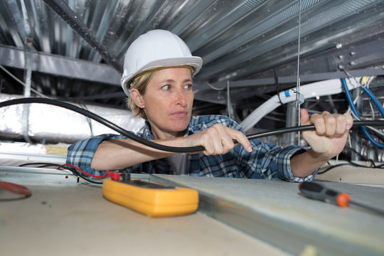 female electrician installing ventilation in ceiling