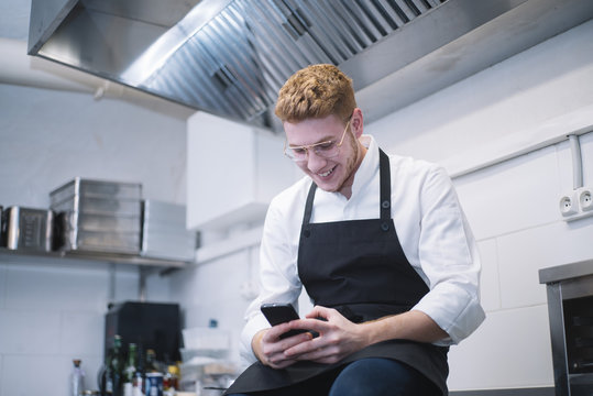Young cook using smartphone in kitchen