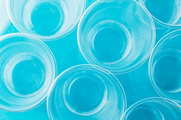 Top view of new clean empty transparent disposable plastic glasses on bright blue background