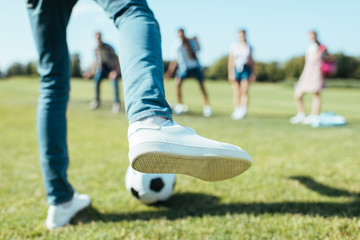 cropped shot of boy playing soccer with friends in park