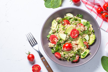 Quinoa salad with spinach, avocado and tomatoes top view.