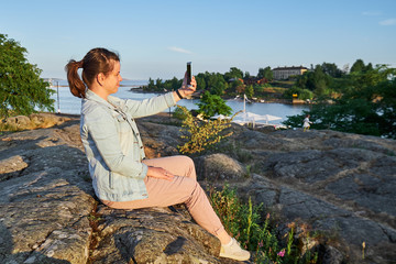 woman taking a selfie. Finland, Helsinki, Kaivopuisto park