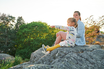 Daughter and her mother sitting on the stone and looking at far away
