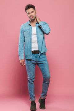 handsome man wearing undone denim shirt and jeans standing