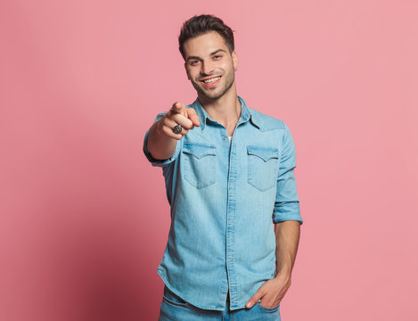 portrait of smiling casual man in denim shirt pointing finger