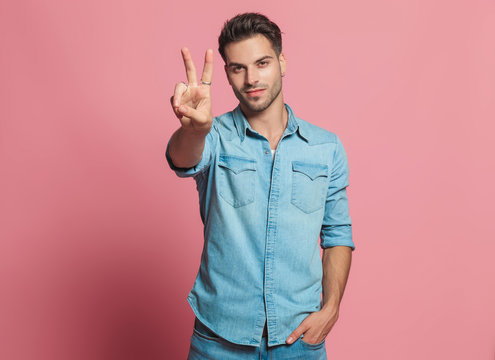 casual man makes peace sign while holding his pocket