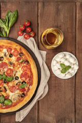 Pepperoni pizza closeup with white wine, ingredients, and place for text
