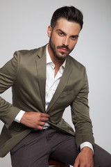 portrait of seated handsome man wearing a green suit