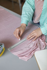 Close up tailor drawing with soap on pink textile in sewing workshop