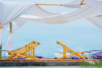 View of communication, beach chair and wooden arch with tropical beach and blue sky.