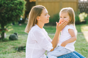 Fototapeta premium side view of mother and little daughter on backyard