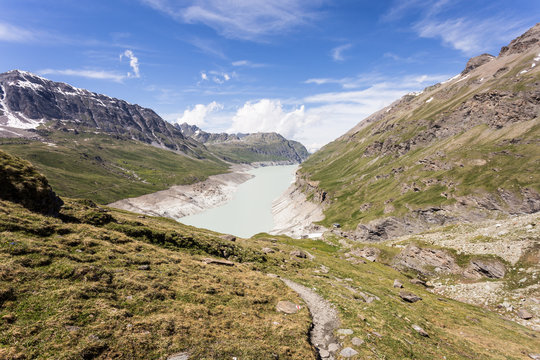 Hiking trail to the Grande Dixence lake, formed by a dam, in the Swiss alps in Canton Valais on a sunny summer day