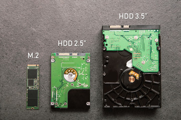Three drives arranged on a stone slab. Comparison of SSD M.2 drive with HDD 2.5