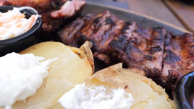 Hot griled appetite ribs with vegetables grill, baked potatos, white creamy sauce, red B-B-Q sause, restaurant fresh air dish