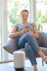 Obraz premium Woman Streams Music From Mobile Phone To Wireless Speaker