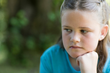 Close Up Of Unhappy Girl Sitting Outdoors In Garden