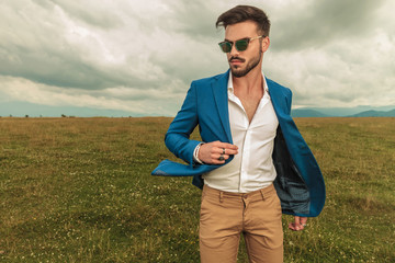 handsome man in suit standing outside and looking to side