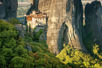 Beautiful scenic view, Orthodox Monastery of Rousanou (St. Barbara), immense monolithic pillar, green and yellow foliage at the background of stone wall in Meteora, Greece, Europe