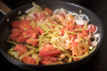 Eggs with tomatoes, green peppers and onions in a frying pan
