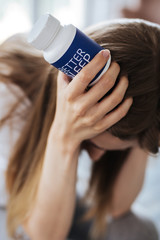 Misery. Miserable blond woman sitting and looking at her sleeping pills
