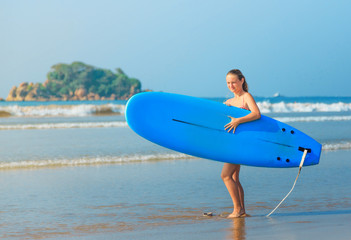 white blonde surfer girl holding surfboard goes to sea