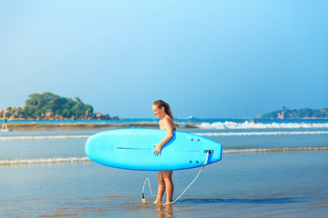 white blonde surfer girl holding surfboard goes to sea