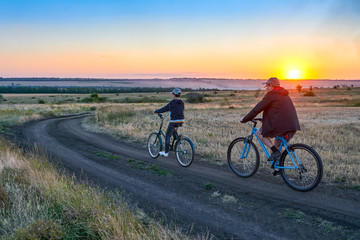 Fototapeta na wymiar father and son ride a bike in the country on the field in the evening