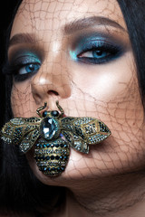 Fashion beauty look of a girl with professional evening makeup, perfect shining skin, dark hair and...