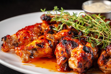 Mexican cuisine, fried chicken wings in glazed hot sauce with thyme on a white plate with tartar sauce. concept beautiful serve in the restaurant. photon image.
