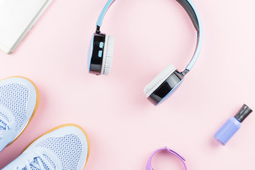 Woman sneakers, headphones, fitness tracker and smartphone on pastel pink background. Sport fashion concept. Flat lay