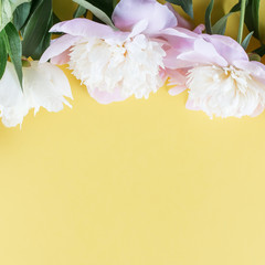 Pastel pink peony flowers bouquet on yellow background. Minimal floral flatlay concept.