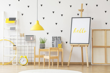 Poster mockup next to a little wooden desk with and aloe plant on it in a scandi child room...