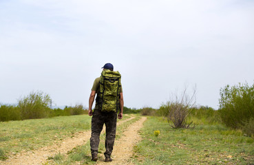 A traveler is walking along the road with a backpack