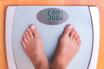 Girl on weighing. Perfect weight for a girl. Libra shows that a girl weighs 50 kg. Weight control_