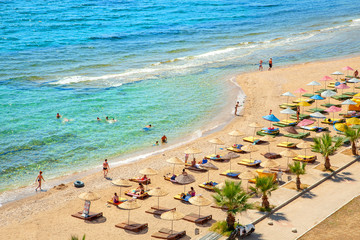 Fototapeta na wymiar Sunbeds with colored umbrellas from the sun on the beach near the sea
