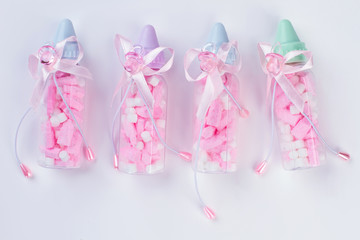 Four baby bottles with pills or sweets and bows.