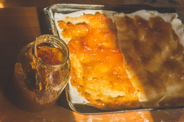 Apple jam next to the baking sheet of rolled dough